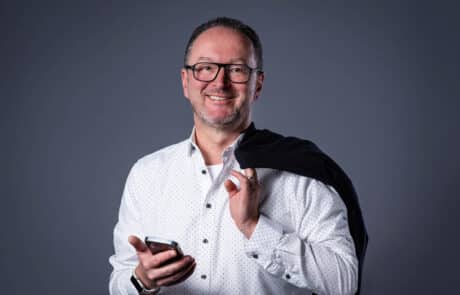 Mann mit Handy und Jacke über der Schulter